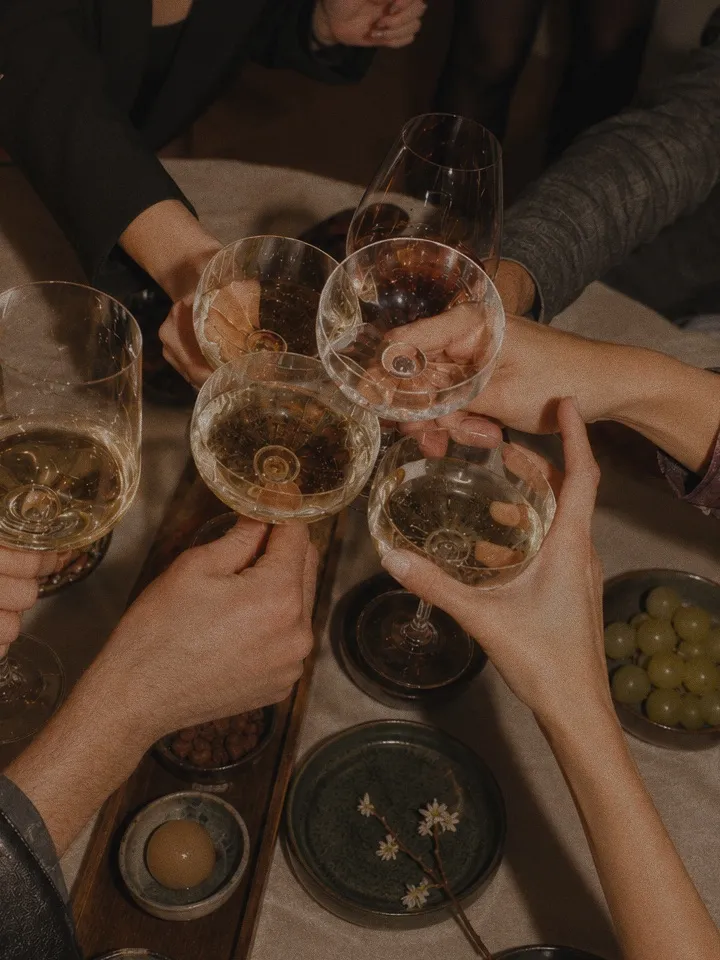 Friends raising glasses in a toast around a candlelit dinner table