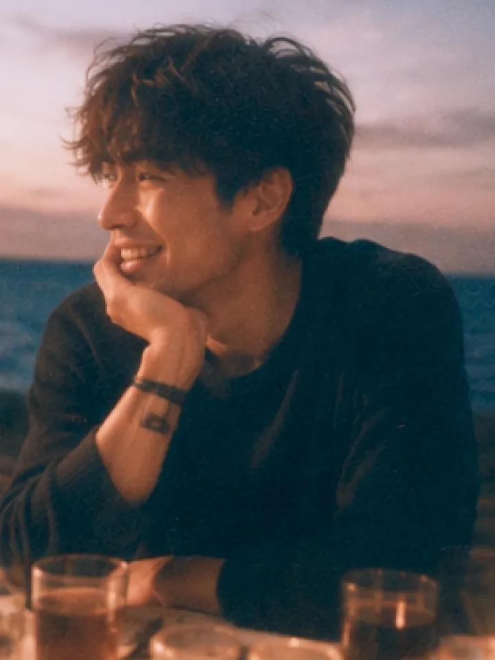 A man smiling at golden hour beside the sea
